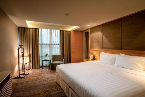 a hotel room with a large bed and a chair at Lao Plaza Hotel in Vientiane
