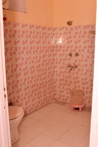 a bathroom with a toilet and pink wallpaper at Hotel Annapurna in Dharamshala