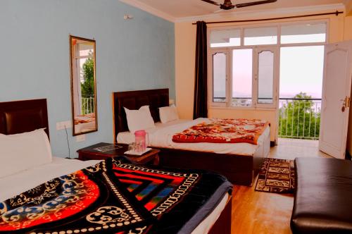 a bedroom with two beds and a couch and a window at Hotel Annapurna in Dharamshala