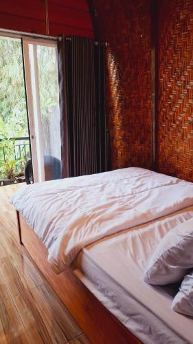 a bed in a room with a large window at Bamboo Craft Homestay in Sangyang