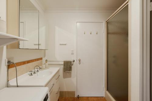a white bathroom with a sink and a shower at River Reach Chalet - Cosy Forest Hideaway in Margaret River Town