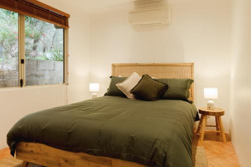 a bedroom with a large green bed with two lamps at River Reach Chalet - Cosy Forest Hideaway in Margaret River Town