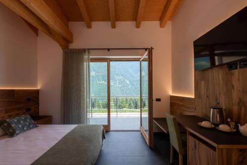 ein Schlafzimmer mit einem Bett und einem großen Fenster in der Unterkunft Malga Prefaè in Commezzadura