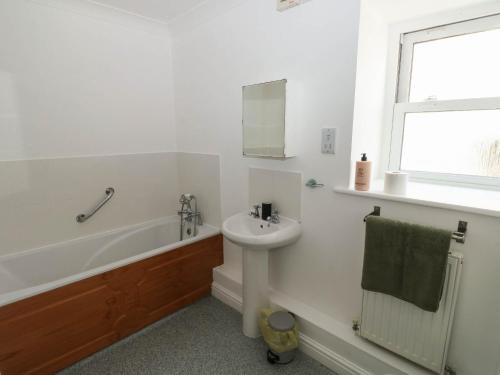 a white bathroom with a sink and a bath tub and a sink at Flat 1 in Newton Abbot