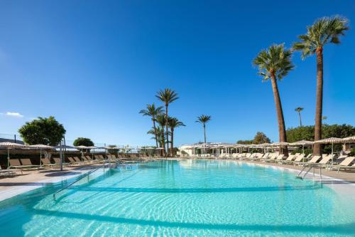 a swimming pool with chairs and palm trees at SOL by Meliá Arona Tenerife in Los Cristianos