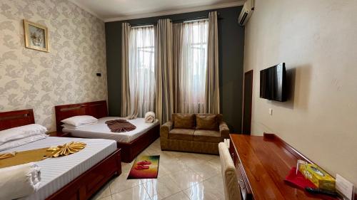 a room with two beds and a couch and a table at Lush Garden Hotel in Arusha