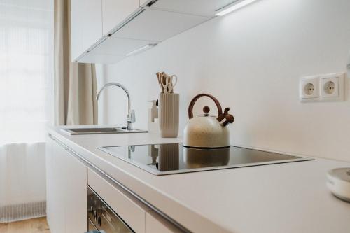 a white kitchen with a tea kettle on the counter at Boho - Suites I BRIGHT-Collection in Koblenz
