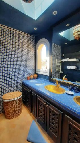 a blue bathroom with two sinks and a window at Auberge Dar Najmat in Mirleft