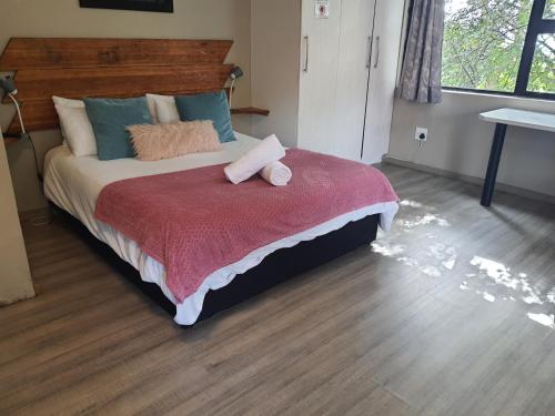 a bedroom with a large bed with a red blanket at The Crooked Forest in Pretoria