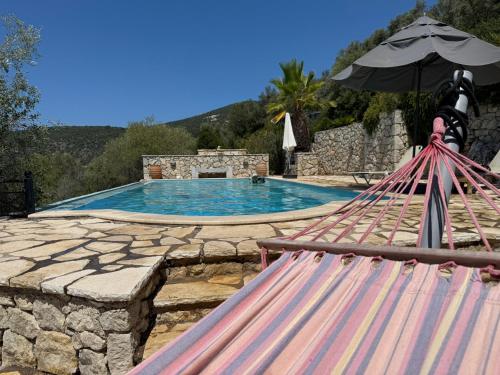 a swimming pool with an umbrella and a hammock at villa amouso in Évyiros