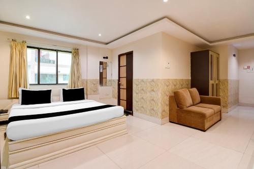 a bedroom with a large bed and a chair at Townhouse Deshapriya Park Kolkata Formerly DK Inn in Kolkata