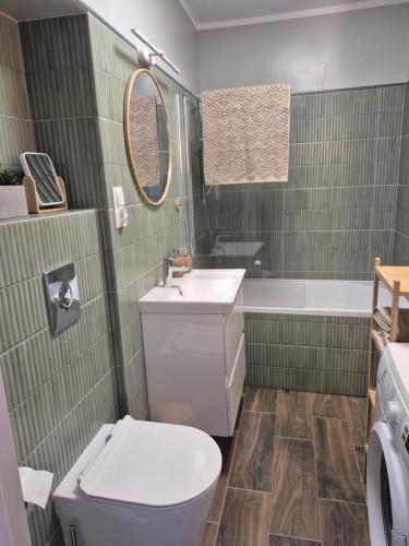 a bathroom with a toilet and a sink and a tub at Apartament HARMONY in Koszalin