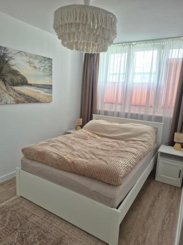 a bedroom with a bed with a chandelier at Apartament HARMONY in Koszalin