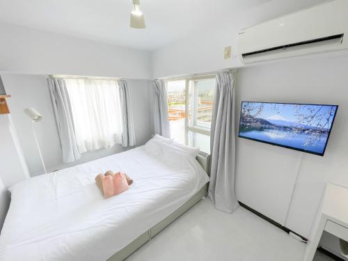 a bedroom with a bed with a tv on the wall at Kameari 1111 - 11F Newly Renovated High Floor City View 2min to Mall 5min to Station Disney Access in Tokyo