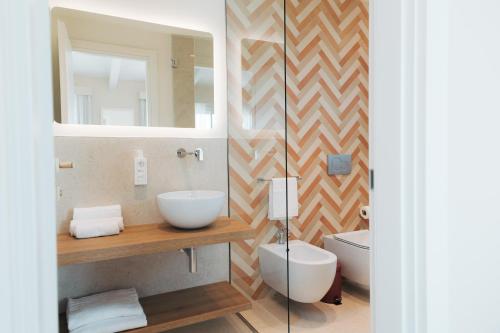 a bathroom with a sink and a toilet and a mirror at PALAZZO RUBINO Aparthotel in Olbia