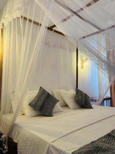 a bed with white curtains and pillows on it at Sky Mountain Café with seaview in Weligama