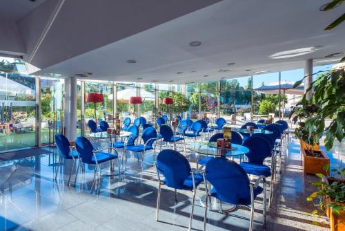 a room with blue chairs and tables and windows at SOL by Meliá Port Cambrils in Cambrils