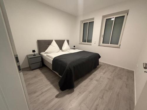 a bedroom with a bed with a black blanket and two windows at Edi`s Ferienwohnung in Eltmann