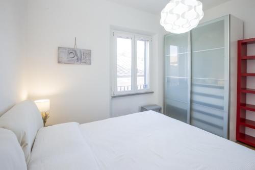 - une chambre blanche avec un lit blanc et une fenêtre dans l'établissement Nila Apartment, à Porto Azzurro