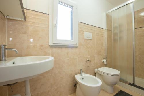 La salle de bains est pourvue d'un lavabo, de toilettes et d'une fenêtre. dans l'établissement Nila Apartment, à Porto Azzurro