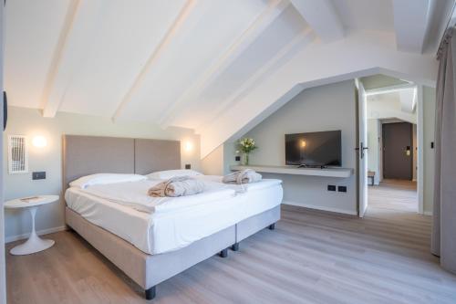 a bedroom with two white beds and a television at Alchimia WellResort in Comano Terme