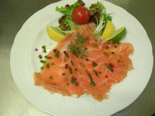 a white plate with a piece of fish and a salad at Logis Le Relais de Sassenage in Sassenage
