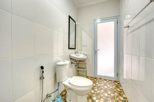a white bathroom with a toilet and a sink at narayuka house in Seminyak