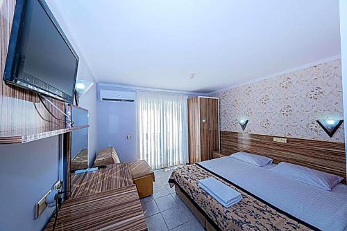 a bedroom with a bed and a flat screen tv at Elysium Elite Hotel in Kızılot