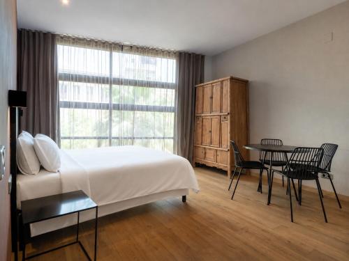 a bedroom with a bed and a table and a window at Aspasios Born in Barcelona