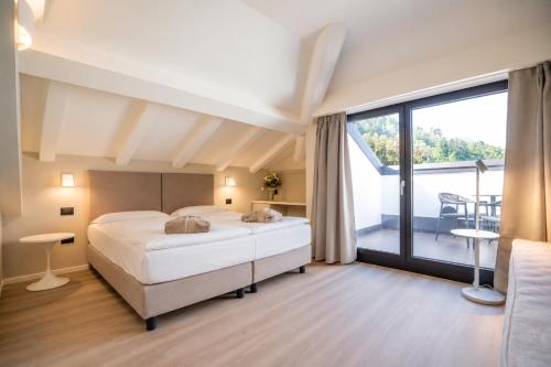 a bedroom with a large bed and a balcony at Alchimia WellResort in Comano Terme