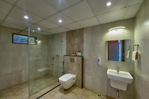 a bathroom with a toilet and a sink and a shower at Coffee Grove Resort in Chikmagalūr