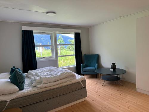 a bedroom with a bed and a table and two windows at Villa Fresvik in Fresvik