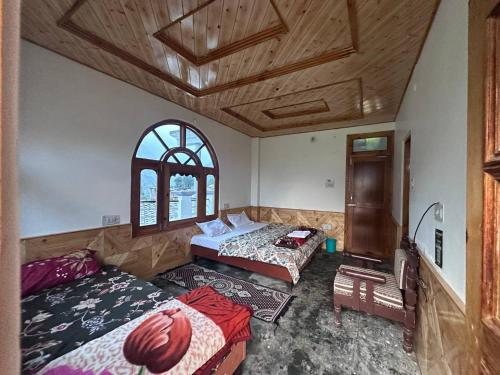 a bedroom with two beds and a window at Boom Shankar in Kalgha