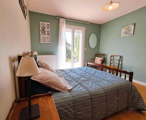 a bedroom with a bed with a blue blanket and a window at La maison vautier in Vendeuvre-sur-Barse