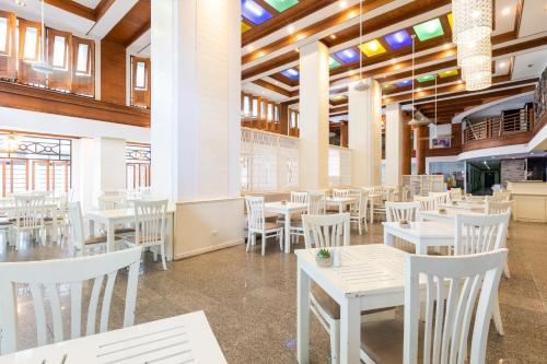 a dining room with white tables and white chairs at Amata Patong in Patong Beach