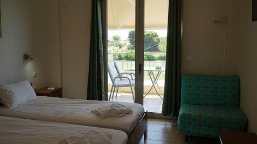 ein Schlafzimmer mit Bett, Stuhl und Balkon in der Unterkunft Asfodelos Apartment Hotel in Kakovatos
