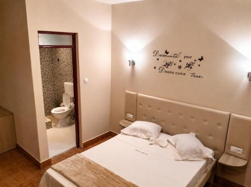a bedroom with a bed and a bathroom with a toilet at Pensão Asa Branca in Assomada