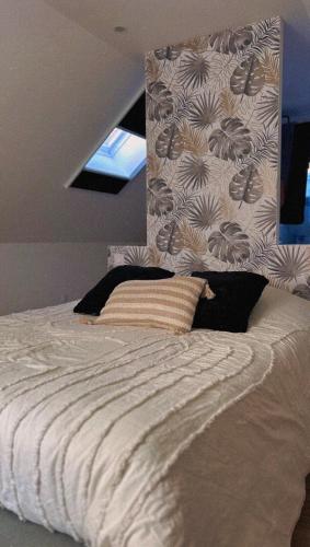 a bedroom with a large white bed with a wall at L'instant Cosy in Gamaches