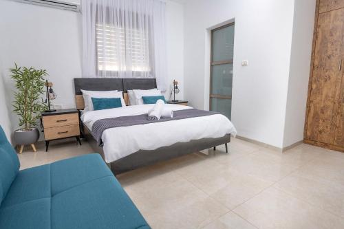a bedroom with a large bed and a blue couch at Villa Glory in Even Menahem