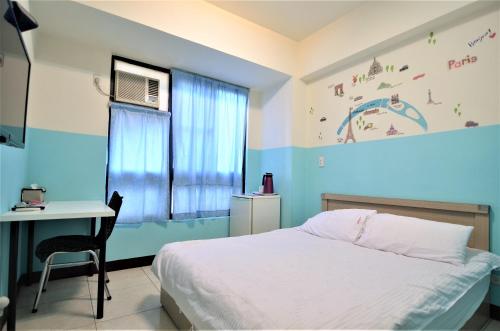 a bedroom with a bed and a desk and a window at Love Fengchia in Taichung