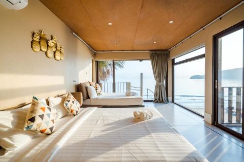 a bedroom with a large bed with a view of the ocean at Cozy Beachfront Samroiyod in Baanphakrimlay 