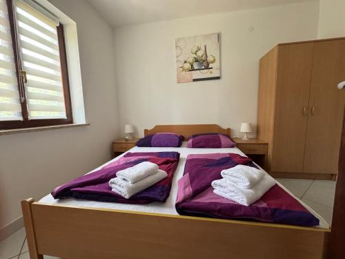 a bedroom with a bed with purple sheets and white pillows at Green House Villa with Pool in Banjole