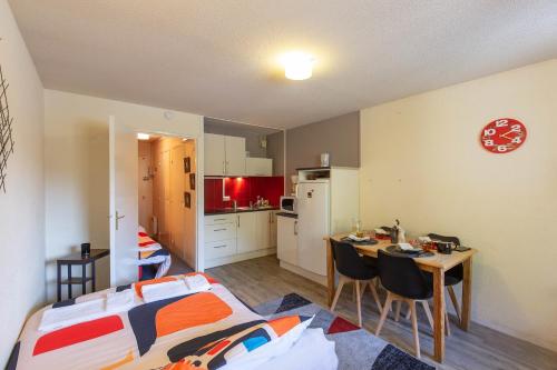 a room with a bed and a table and a kitchen at La Mongie Parking Petfriendly in Bagnères-de-Bigorre