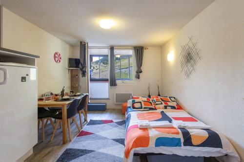 a room with two beds and a table and a kitchen at La Mongie Parking Petfriendly in Bagnères-de-Bigorre