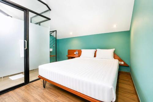 a bedroom with a white bed and a blue wall at Noesa Heritage in Surabaya