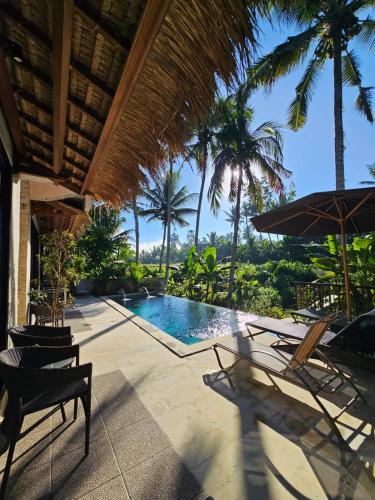 a pool with chairs and an umbrella and palm trees at Bali View Ubud Hotel in Ubud