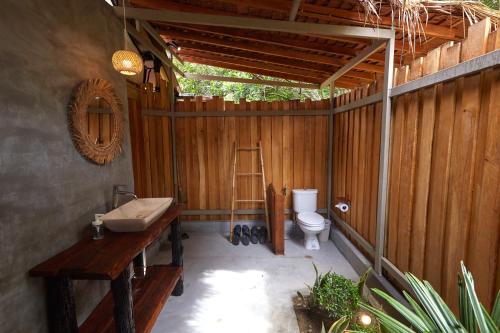 a bathroom with a toilet and a wooden wall at The Woods Beachfront Tent Yao Noi in Ko Yao Noi