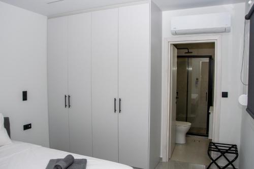 a white bedroom with a bed and a bathroom at COMFY Apartments in Alexandroupoli