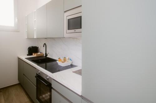 a white kitchen with a sink and a microwave at Erigia House - Appartamenti Eleganti - Molfetta in Molfetta