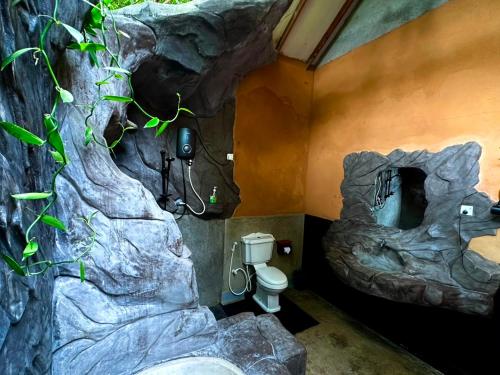 a bathroom with a rock wall with a toilet at Ama Eco Lodge in Sigiriya